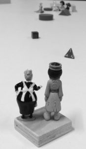 Zwei sehr kleine Figuren stehen mit dem Rücken zum Betrachter und blicken voraus auf kleine Hindernisse.